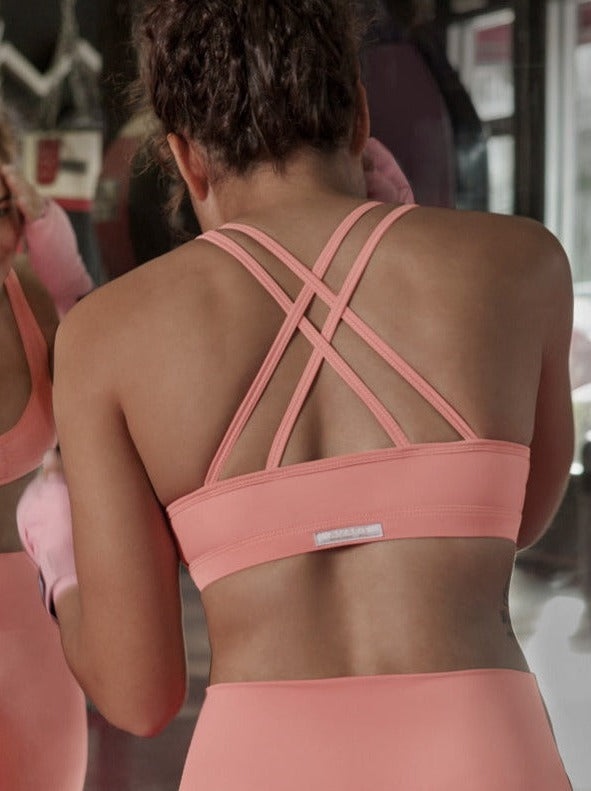 model standing infront of a mirror wearing a crossback sports bra in pink